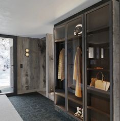 a room with wooden walls and shelves filled with coats, shoes and handbags