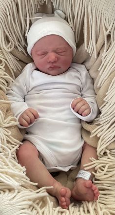 a newborn baby wrapped in a blanket and wearing a white knitted hat is laying down