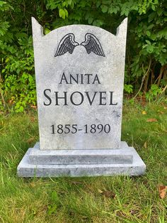 a headstone in the grass with an angel on it's head and name