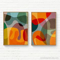 two abstract paintings hanging on a white brick wall next to each other in different colors