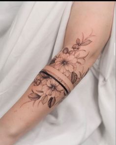 a woman's arm with flowers on it and a band around the wrist tattoo