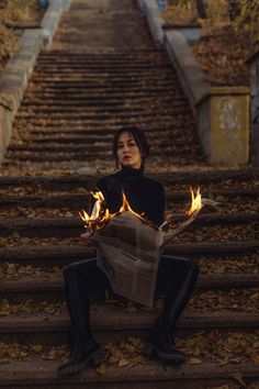 a woman sitting on the steps with fire in her hands