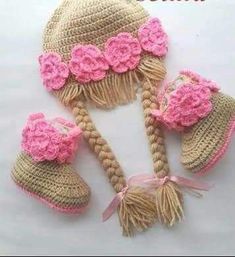 three crocheted hats and booties with pink flowers on the top one is made out of yarn