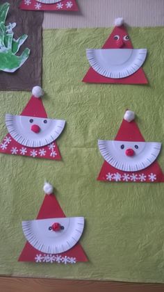 some paper plates with santa hats on them and snowflakes hanging from the wall