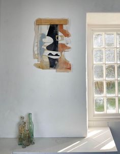 an abstract painting hangs on the wall next to a window