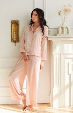 Details Let our classic charmeuse Heavenly Pajamas be your go-to 'staying-in' loungewear this season. Designed in our classic silky charmeuse fabric, these luxury pajamas feel ultra soft against the skin while giving off a lustrous sheen. Our timeless blush hue pairs perfectly with the natural look of the charmeuse fabric giving off an ethereal radiance. Mother of pearl buttons and piping detail add further touches of elegance and sophistication, while the wide-leg pajama pants do the same on th Relaxed Fit Satin Sleepwear For Loungewear, Elegant Satin Loungewear, Elegant Satin Sleepwear For Lounging, Feminine Silk Sleepwear, Silk Sleepwear For Spring Season, Spring Silk Sleepwear, Elegant Sleepwear For Pajama Party, Chic Satin Sleepwear For Loungewear, Elegant Relax Fit Sleepwear For Pajama Party