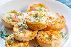 several small pastries on a white plate with green garnish and sprigs