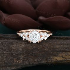 an engagement ring with three diamonds on top of a piece of wood next to a teddy bear