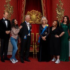 a group of people standing next to each other in front of a red and gold wall