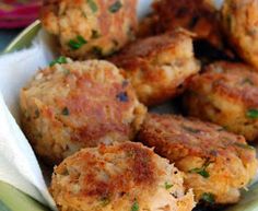 some crab cakes are in a green and white bowl on a table with other food items