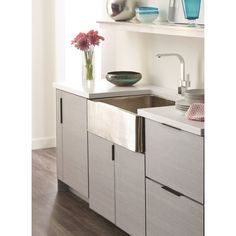 a kitchen sink sitting under a window next to a shelf with vases on it