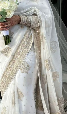 a woman in a white sari holding a bouquet of flowers