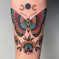 a colorful butterfly tattoo on the leg with flowers and moon in it's wings