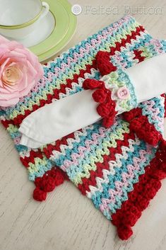 crocheted dishcloths and napkins on a table with a pink rose