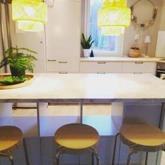 three stools sit at the center of a kitchen island in front of a window