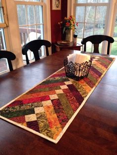 a table runner with a crown on it in front of two black chairs and windows