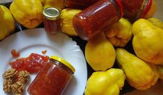 there are two jars of jam on the plate next to some lemons and nuts