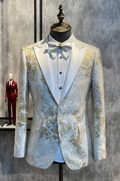 a white tuxedo jacket with gold and silver designs on the lapel stands next to a mannequin wearing a red suit