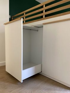 an empty closet underneath a bed in a room with wood flooring and green walls