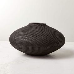 a black vase sitting on top of a white table