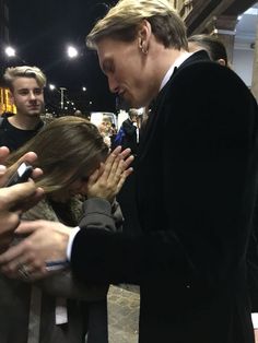 a man in a suit and tie is surrounded by people