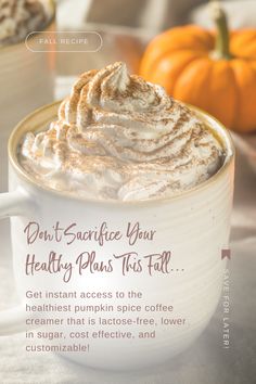 a cup of hot chocolate with whipped cream on top and pumpkins in the background