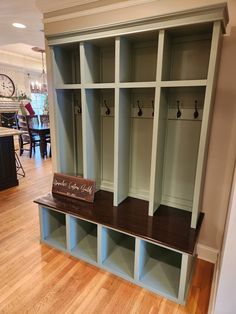 a wooden bench sitting in the middle of a room next to a wall mounted coat rack