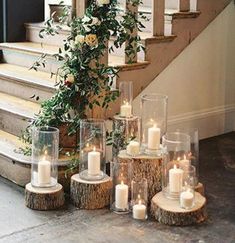 candles and flowers are arranged on wooden logs in front of the stairs at this wedding venue