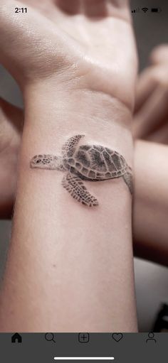 a woman's arm with a small tattoo of a sea turtle on the wrist