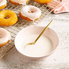 doughnuts cooling on a rack with a bowl of milk