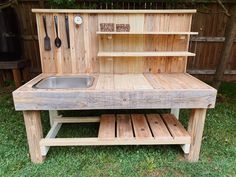 an outdoor kitchen made out of pallets and wooden planks with a sink in the center