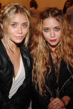 two beautiful young women sitting next to each other in front of a group of people