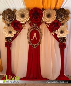 a decorated stage with red and white drapes, gold accents and large paper flowers