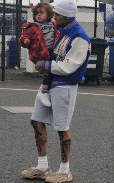 a man holding a small child on top of his back while standing in the street