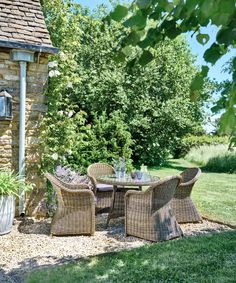 an outdoor table and chairs in front of a stone building