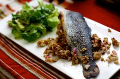 a white plate topped with fish next to a pile of salad and lettuce