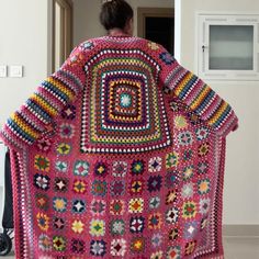 a woman is holding up a crocheted blanket