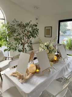 a table set up with white chairs and flowers