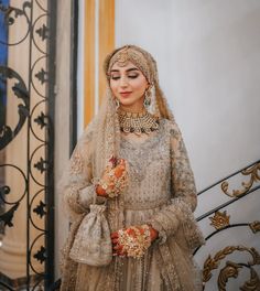 a woman in a bridal outfit standing next to a staircase