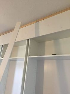 an unfinished closet with shelves and ladders on the wall above it is being painted white