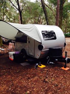 an rv is parked in the woods with its awning open and it's bed pulled up