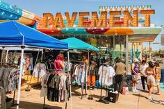 several people are standing in front of tents with shirts on them and the words pavement written above them