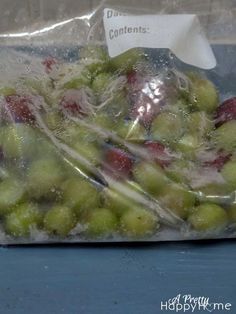 a bag filled with lots of green and red fruit sitting on top of a table