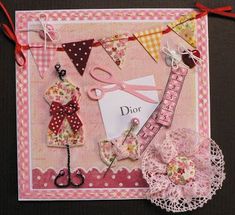 a pink card with scissors and other crafting items hanging from it's sides