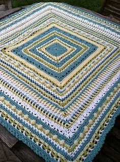 a crocheted blanket sitting on top of a wooden bench