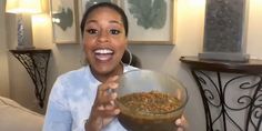 a woman is holding a bowl of food in her hand and smiling at the camera