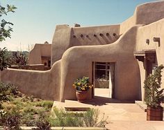 an adobe - style building with potted plants in front