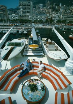 two people sitting on the back of a boat in front of a cityscape