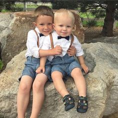 two young boys sitting next to each other on top of a rock