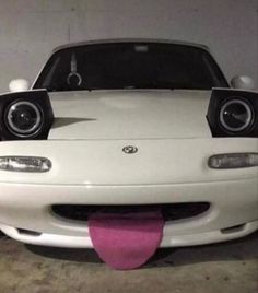 the front end of a white sports car with two speakers on it's hood